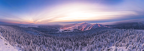 Aerial panoramic view of snowy forest and ski slopes under the dramatic sky at sunset, Ruka, Kuusamo, Northern Ostrobothnia, Lapland, Finland