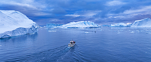 Aerial of a boat between the icebergs of the Ilulissat Icefjord, UNESCO World Heritage Site, Western Greenland, Denmark, Polar Regions