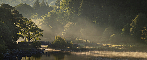 Footbridge crossing Nant Gwyd and Llynnau Mymbyr at sunrise with morning mist, Capel Curig, Snowdonia National Park, Wales, United Kingdom, Europe