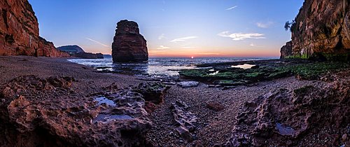 Dawn on the beach with one of the majestic sea stacks at Ladram Bay, Sidmouth, Devon, UK