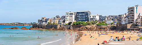 : A wide panoramic view of Rochebonne Beach in Brittany, France, filled with sunbathers and swimmers enjoying the summer sun.