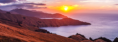 Panorama of Vibrant sunset over the rugged coastline and golden hills of French Pass, Marlborough Sounds, South Island, New Zealand