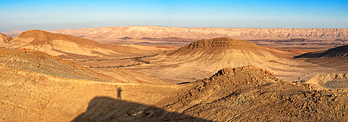 Panoramic view of Negev desert with shadow silhouette of a man on the mountain peak in sunrise