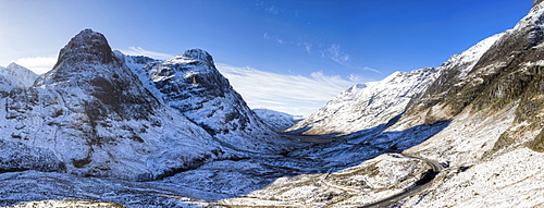 Winter view down snow-covered Glencoe showing Three Sisters of Glencoe and the A83 winding through the glen towards Glencoe Village, Highland, Scotland, United Kingdom, Europe