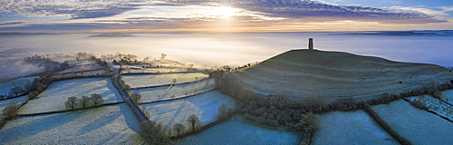 Aerial view by drone of frosty winter sunrise over Glastonbury Tor, Somerset, England, United Kingdom, Europe