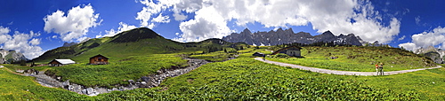 Panorama at the Ladizalm alipine pasture with Lalidererwaende Cliffs, hikers, meadows and clouds in the Karwendel Range, Tyrol, Austria, Europe