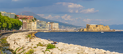 View of pastel coloured architecture, restaurants and Ovo Castle on seafront of Via Partenope and Mount Vesuvius, Naples, Campania, Italy, Europe