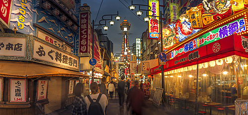 View of Tsutenkaku Tower and restaurants neon lights at night in the Shinsekai area, Osaka, Honshu, Japan