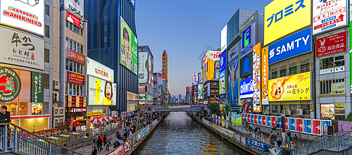 View of restaurants and tour boat in Dotonbori, vibrant entertainment district near the river, Osaka, Honshu, Japan