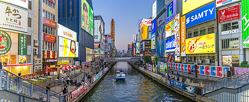 View of tour boat, restaurants and tour boat in Dotonbori, vibrant entertainment district near the river, Osaka, Honshu, Japan