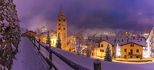 View of Church of Saint Pantalon and the snow covered town centre and mountainous background in winter at dusk, Courmayeur, Aosta Valley, Italy, Europe