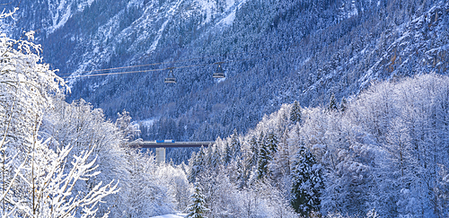 Snow covered trees, mountains and cable car from Courmayeur to Plan Chécrouit viewed from Courmayeur during winter, Courmayeur, Aosta Valley, Italy, Europe