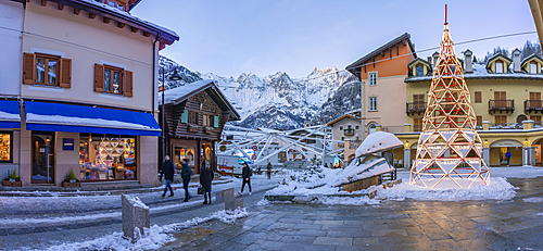 View of shops, town centre and snow covered mountains in Courmayeur at dusk during Christmas, Courmayeur, Aosta Valley, Italy, Europe