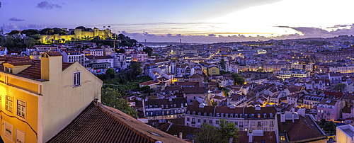Panoramic view of Lisbon Castle from Miradouro da Senhora do Monte scenic point at dusk in the Alfama District, Lisbon, Portugal, Europe