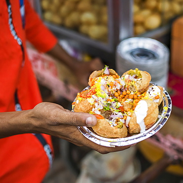 A hand holding a foil plate with a serving of traditional Indian food, Jaipur, Rajasthan, India