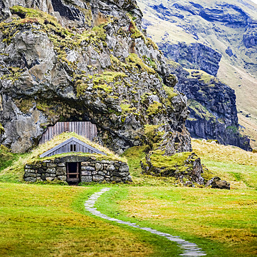 Barn built into a rocky mountainside, now overgrown with grass; Rangarping eystra, Southern Region, Iceland