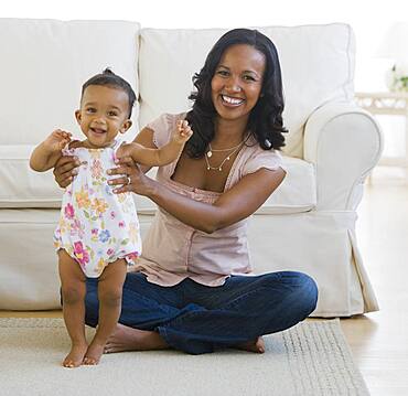 African American mother helping baby stand