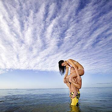 Pacific Islander woman sitting on boyfriend's shoulders