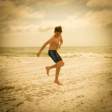 Caucasian boy jumping and splashing in ocean waves