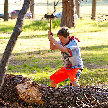 Caucasian boy chopping log with axe