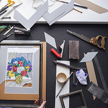 Hand holding picture frame near tools on table