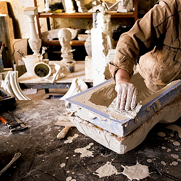 Caucasian artist scraping plaster in mold