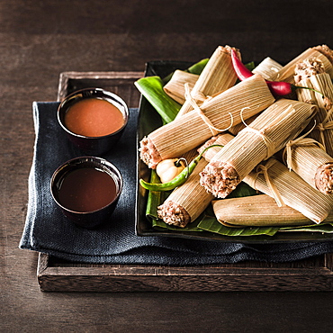 Tamales and dips on wooden tray