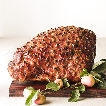 Cooked glazed ham on wooden cutting board