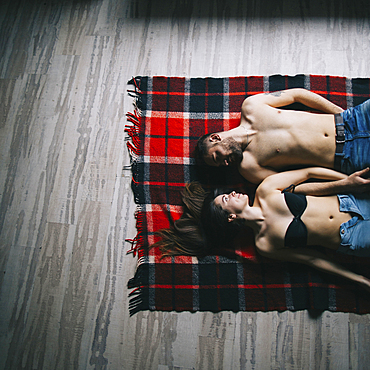 Caucasian couple laying face to face on plaid blanket