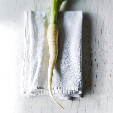 White carrot on napkin on white wooden table