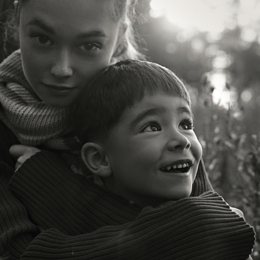 Caucasian women wearing sweater hugging boy