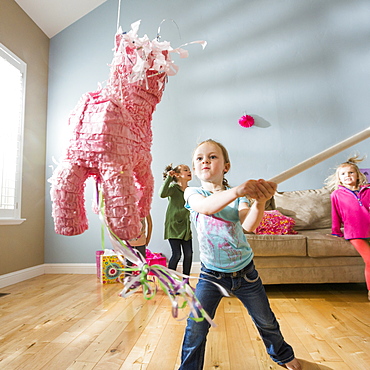 Caucasian girl hitting pinata at party