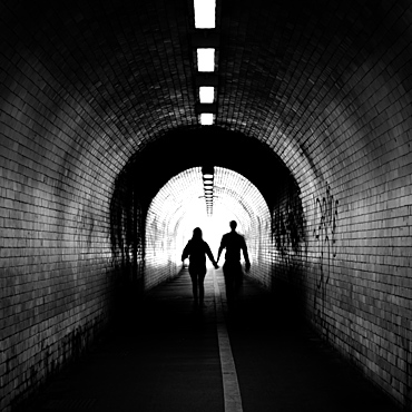 Couple walking into the light, York tunnel, York, England, United Kingdom, Europe