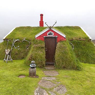 Traditional peat house Lindarbakki overgrown with grass and antlers in the red gable, Bakkageroi, Bakkagerdi, Borgarfjoerour, Borgarfjoerdur, Austurland, Iceland, Europe