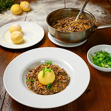 Goulash with chanterelles (Cantharellus cibarius) and a dumpling made of potato dough with a small salad and cooking pot