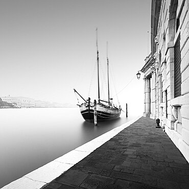 Black and white photograph of the Fondamenta Salute in the fog with a historic sailing ship in Venice, Italy, Europe