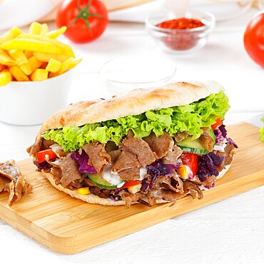 Doener Kebab Doner Kebap fast food meal in pita bread menu with fries on kitchen board square in Stuttgart, Germany, Europe