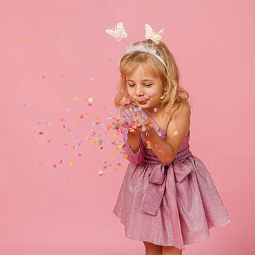 Cute girl blowing confetti