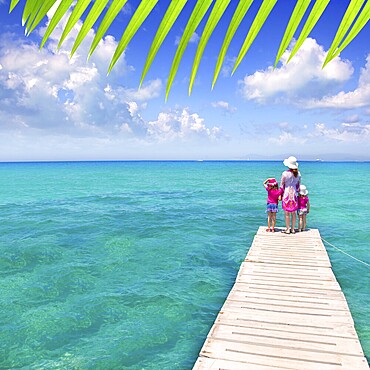 Daughters and mother in jetty on Formentera with turquoise sea