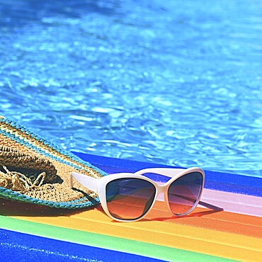 Sunglasses, lilo and hat on the water in hot sunny day. Summer background for traveling and vacation. Holiday idyllic