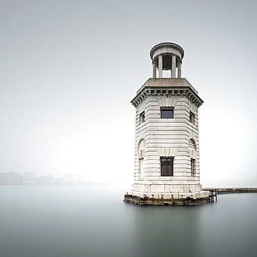 Long exposure of the Faro di San Giorgio lighthouse on the island of San Giorgio Maggiore in foggy weather in Venice, Italy