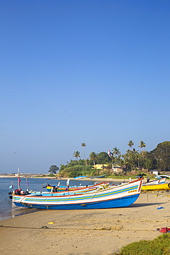 Fishing boats on beach with Tangasseri Lighthouse in background, Kollam, Kerala, India, Asia