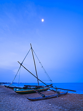 Traditional outrigger fishing boat (oruva) on Negombo Beach at night under the moon, Negombo, Sri Lanka, Asia