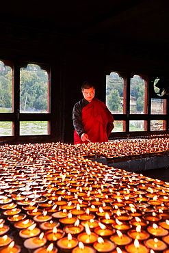 Portrait, Bhutanese Buddhist monk lights candles for worshippers to pray, Tamzhing Monastery, Bumthang District, Bhutan, Asia