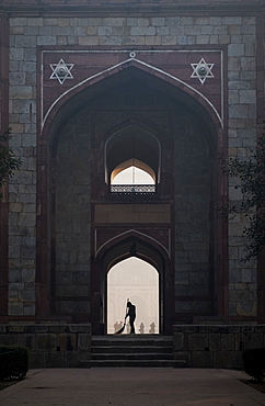 Silhouette of man sweeping under arch of Humayun's Tomb in Delhi, India, Asia