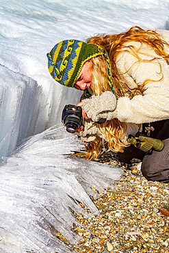 Guest from the Lindblad Expedition ship National Geographic Explorer photographing soda straw ice in the Svalbard Archipelago, Norway.