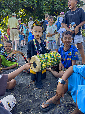 A young ceremonial drummer coming to perform with his ornately painted drum on Sumbawa Island, Indonesia.