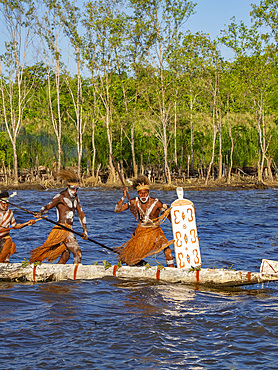 Male paddlers from the village of Per perform in a ritualistic greeting ceremony, Asmat Region, Papua, Indonesia.