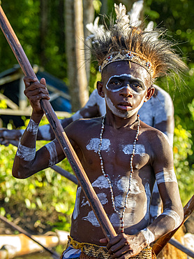 Male paddlers from the village of Per perform in a ritualistic greeting ceremony, Asmat Region, Papua, Indonesia.