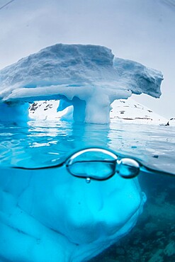 Above and below view of an arch formed in an iceberg at Cuverville Island, Ererra Channel, Antarctica, Polar Regions